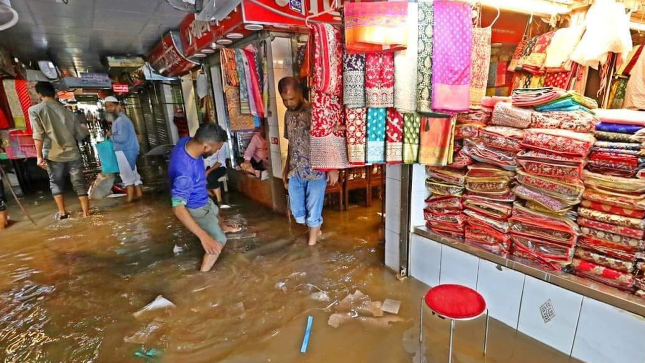 দোকানে পানি ওঠার উপক্রম। আটকে থাকা পানি বের করে দেওয়ার চেষ্টা করছেন ব্যবসায়ীরা। ছবি : কালবেলা