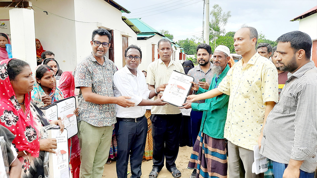 গৃহহীন পরিবারের হাতে প্রধানমন্ত্রী শেখ হাসিনার উপহারের ঘরের কাগজপত্র তুলে দেওয়া হচ্ছে। ছবি : কালবেলা