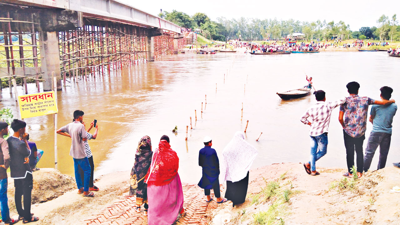 দিনাজপুর জেলার ঘোড়াঘাট এবং গাইবান্ধা জেলার পলাশবাড়ী উপজেলার সীমানায় করতোয়া নদীর ওপর নির্মাণাধীন সেতুর পাশে অস্থায়ী কাঠের সেতু ডুবে গেছে। ছবি : কালবেলা
