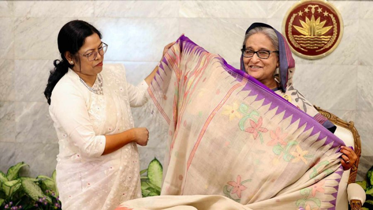 প্রধানমন্ত্রী শেখ হাসিনার হাতে শাড়ি তুলে দিচ্ছেন বান্দরবানের জেলা প্রশাসক। ছবি : সংগৃহীত