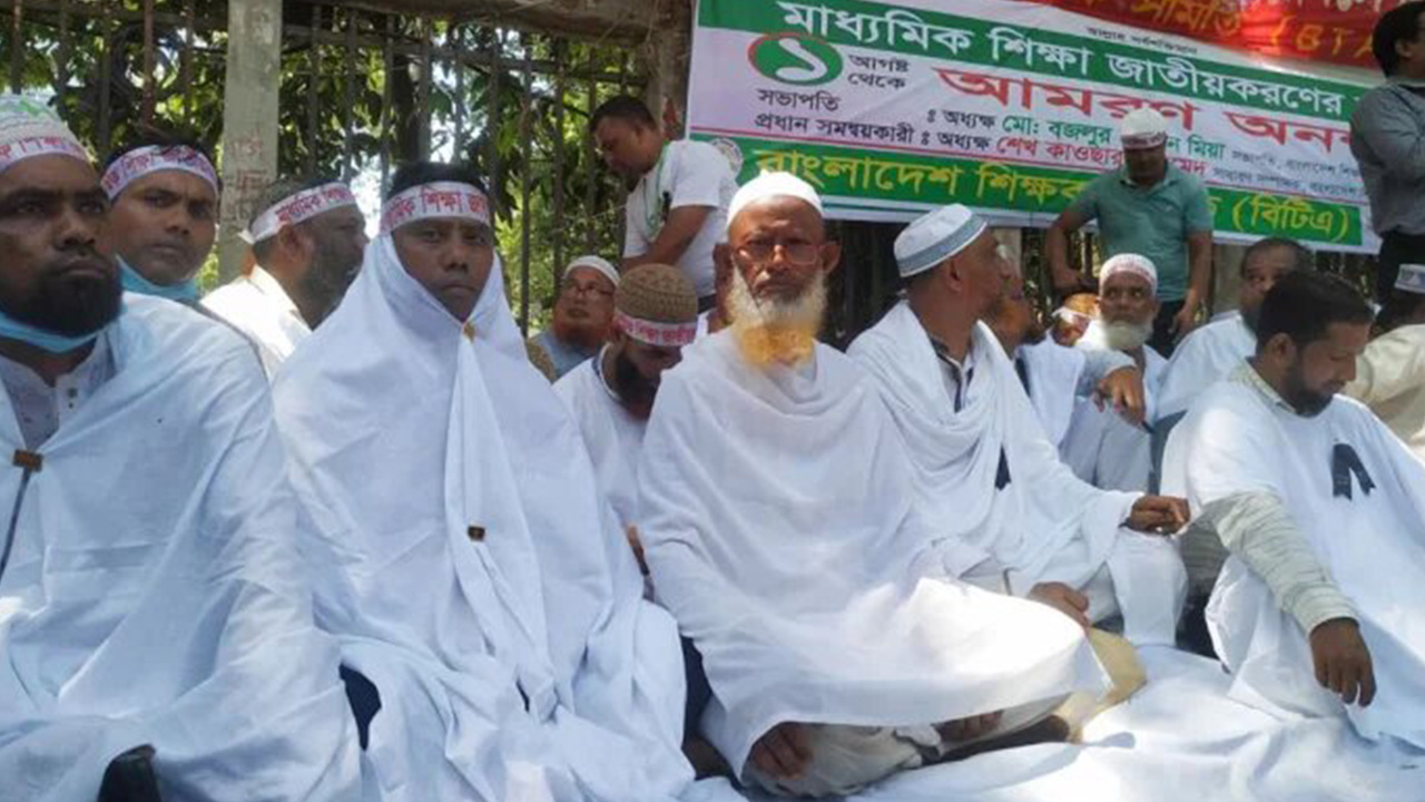 কাফনের কাপড় পরে জাতীয়করণের দাবিতে অনশন করেন শিক্ষকেরা। ছবি : কালবেলা