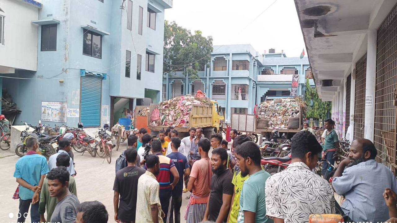 সাতক্ষীরা পৌরসভার পরিচ্ছন্নতাকর্মীরা ময়লার গাড়ি রেখে অবস্থান কর্মসূচি পালন করছেন। ছবি : কালবেলা