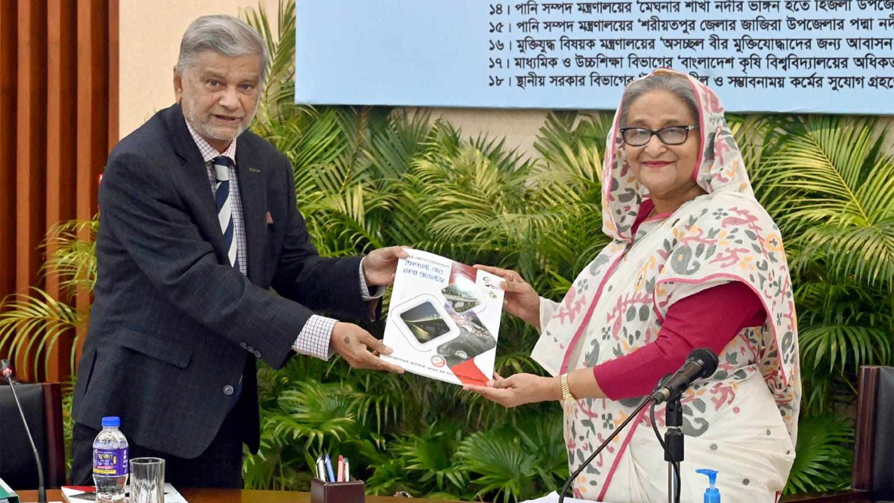 প্রধানমন্ত্রীর হাতে ডিজেএফবির বইটি তুলে দেন পরিকল্পনামন্ত্রী এম এ মান্নান। ছবি: পিআইডি
