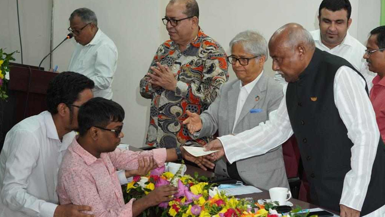 ঢাকা বিশ্ববিদ্যালয়ে অধ্যয়নরত প্রতিবন্ধী শিক্ষার্থীর হাতে অনুদানের চেক তুলে দেন সমাজকল্যাণ মন্ত্রণালয়ের প্রতিমন্ত্রী মো. আশরাফ আলী খান খসরু। ছবি : কালবেলা