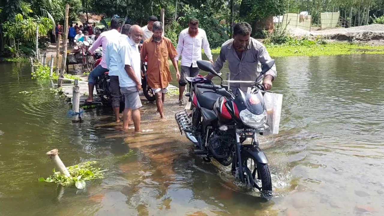 ভারি বর্ষণে ডুবে যাওয়া কাঠের সাঁকো দিয়েই যাতায়াত করছেন স্থানীয়রা। ছবি : কালবেলা