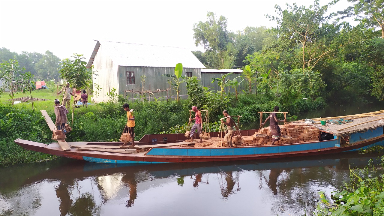 কুমিল্লার ব্রাহ্মণপাড়া খালে ইঞ্জিনচালিত নৌকা থেকে ইট নামাচ্ছেন শ্রমিকরা। ছবি : কালবেলা