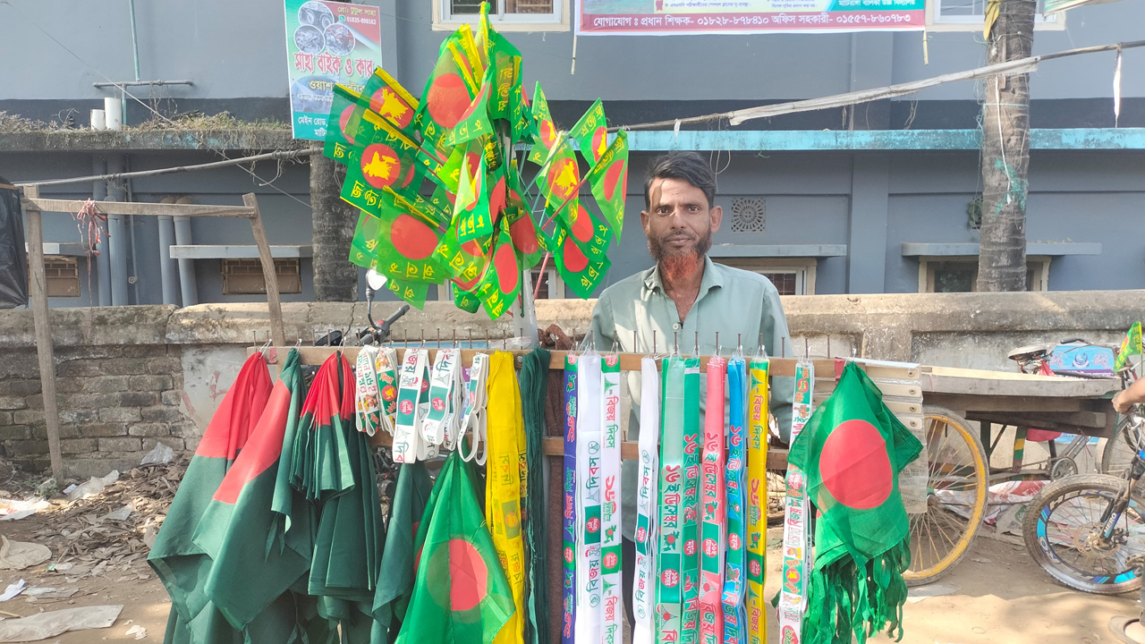 সড়কের পাশে পতাকা হাতে লাল মিয়া। ছবি : কালবেলা