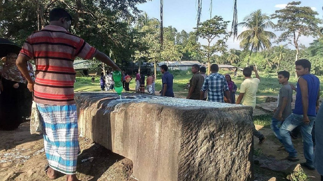মহাস্থানগড়ের বৌদ্ধ মন্দিরের ধ্বংসাবশেষ খোদার পাথর ভিটায় দুধ ঢালছেন এক ভক্ত। ছবি : কালবেলা