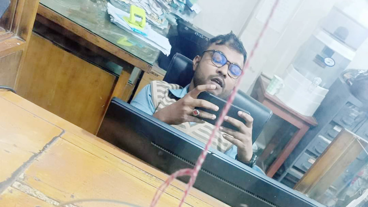 ব্যাংকের ডেস্কের ভেতরে মোবাইল ফোনে গেম খেলায় ব্যস্ত ব্যাংক কর্মকর্তা। ছবি : সংগৃহীত