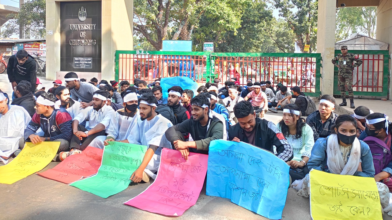 সাদা কাফন ও মাথায় কাপড় বেঁধে হাতে ফেস্টুন নিয়ে আন্দোলন করছেন শিক্ষার্থীরা।
