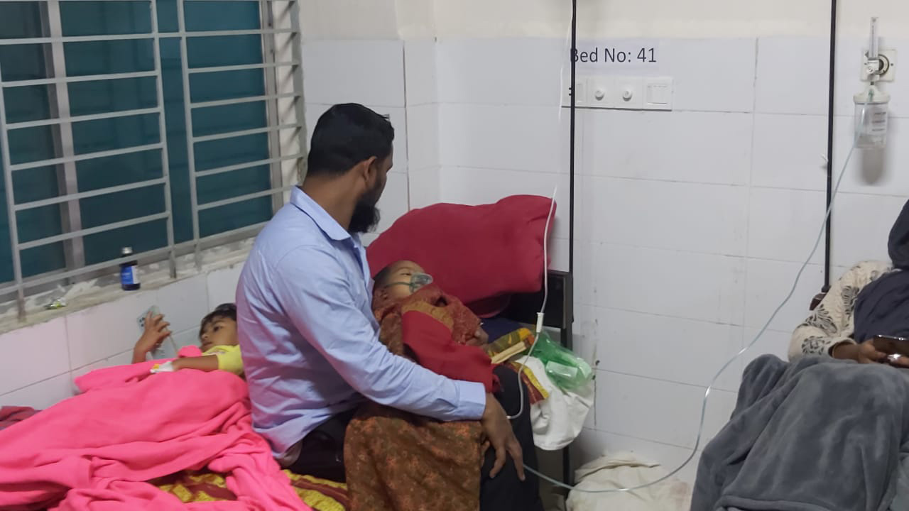 হাসপাতালের বেডে মুখে অক্সিজেন মাস্ক পরা মেজো মেয়ে আমেনাকে কোলে নিয়ে বসে আছেন টিটো মোল্লা। ছবি : কালবেলা