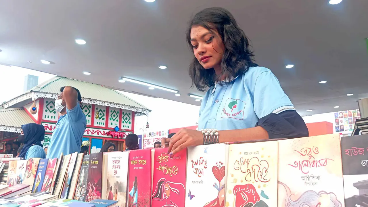 বইমেলার স্টলে নারী বিক্রয়কর্মী। ছবি : কালবেলা