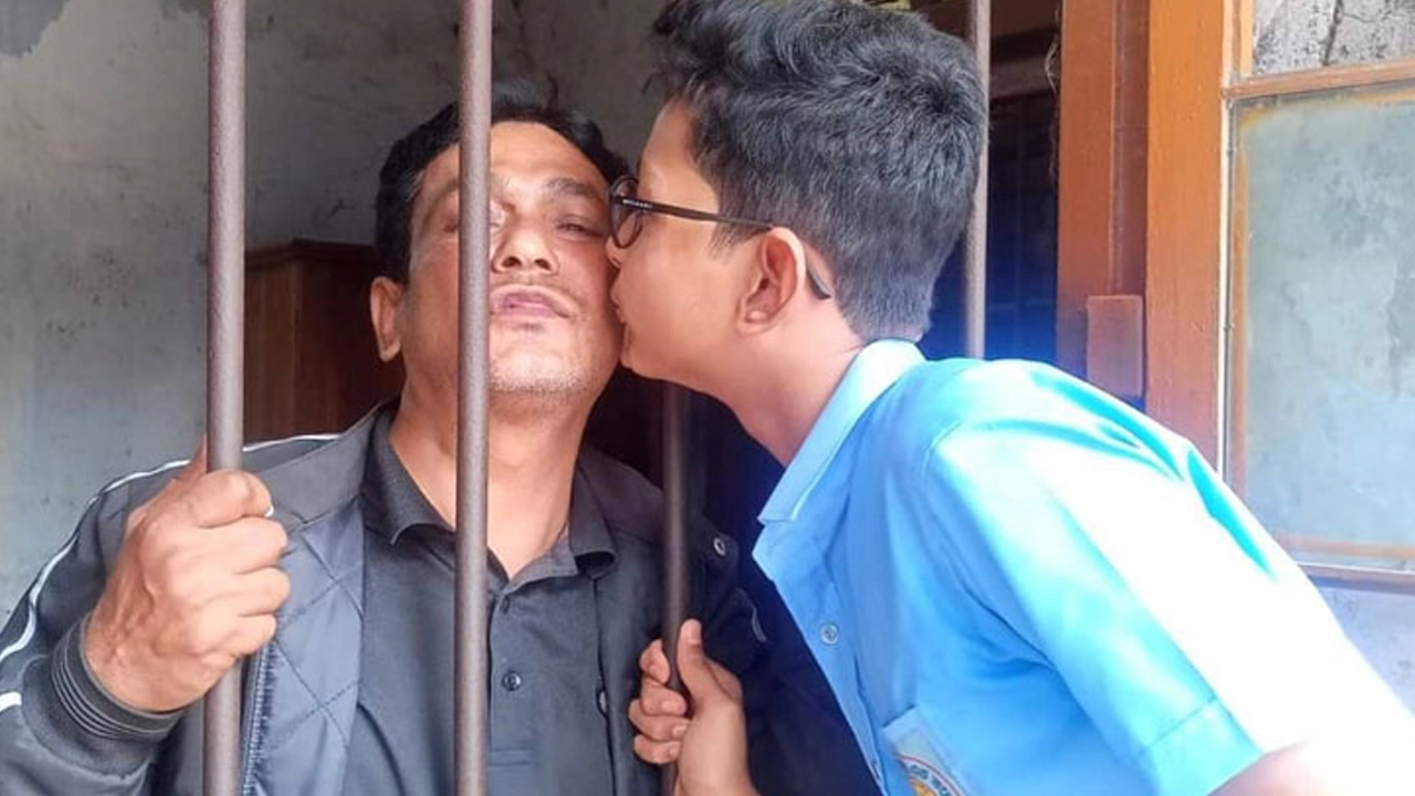 গারদবন্দি বাবাকে চুমু দেয় ছেলে। ছবি : সংগৃহীত