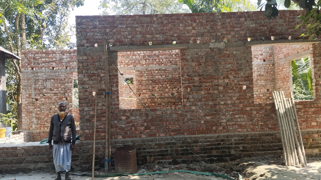 হরিরামপুরে নির্মাণাধীন বীরনিবাসের সামনে দাঁড়িয়ে একজন বীর মুক্তিযোদ্ধা। ছবি : কালবেলা