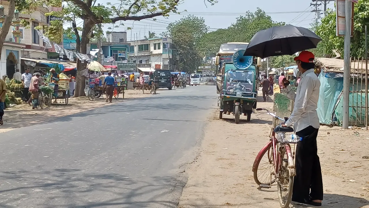 চুয়াডাঙ্গায় তীব্র গরম থেকে বাঁচতে রাস্তাঘাটে ছাতা নিয়ে বের হচ্ছেন অনেকে। ছবি : কালবেলা