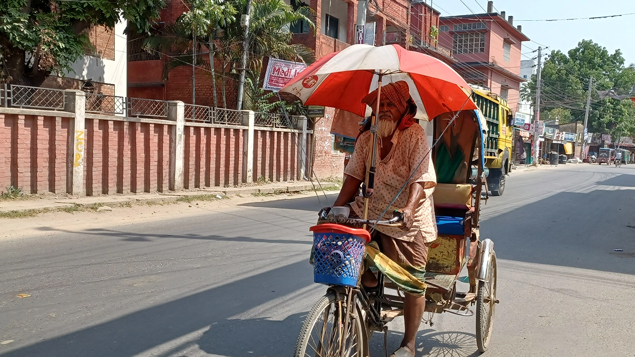 তীব্র রোদ থেকে বাঁচতে রিকশায় ছাতা টানিয়ে রাস্তায় এক চালক। ছবি : কালবেলা