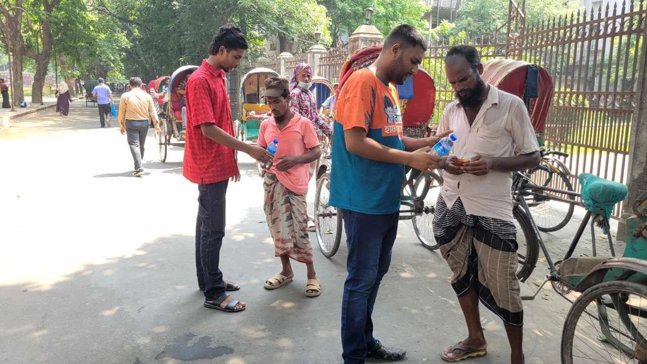 পানি ও স্যালাইন বিতরণ করছেন ঢাবির দুই শিক্ষার্থী। ছবি : কালবেলা