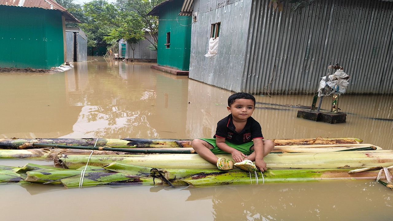 কসবা উপজেলার বায়েক ইউনিয়নের বায়েক গ্রামে ভেলায় বসে আছে একটি শিশু। ছবি : কালবেলা