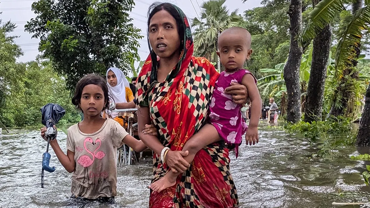 বন্যায় সন্তানকে কোলে করে নিয়ে যাচ্ছেন মা। ছবি : কালবেলা