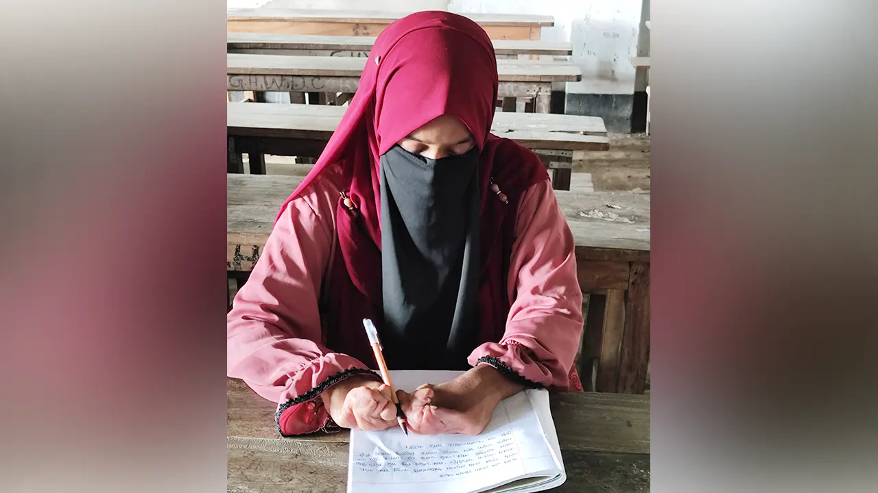 কবজি দিয়ে লিখে পরীক্ষা দেওয়া মিনারা খাতুন। পুরোনো ছবি