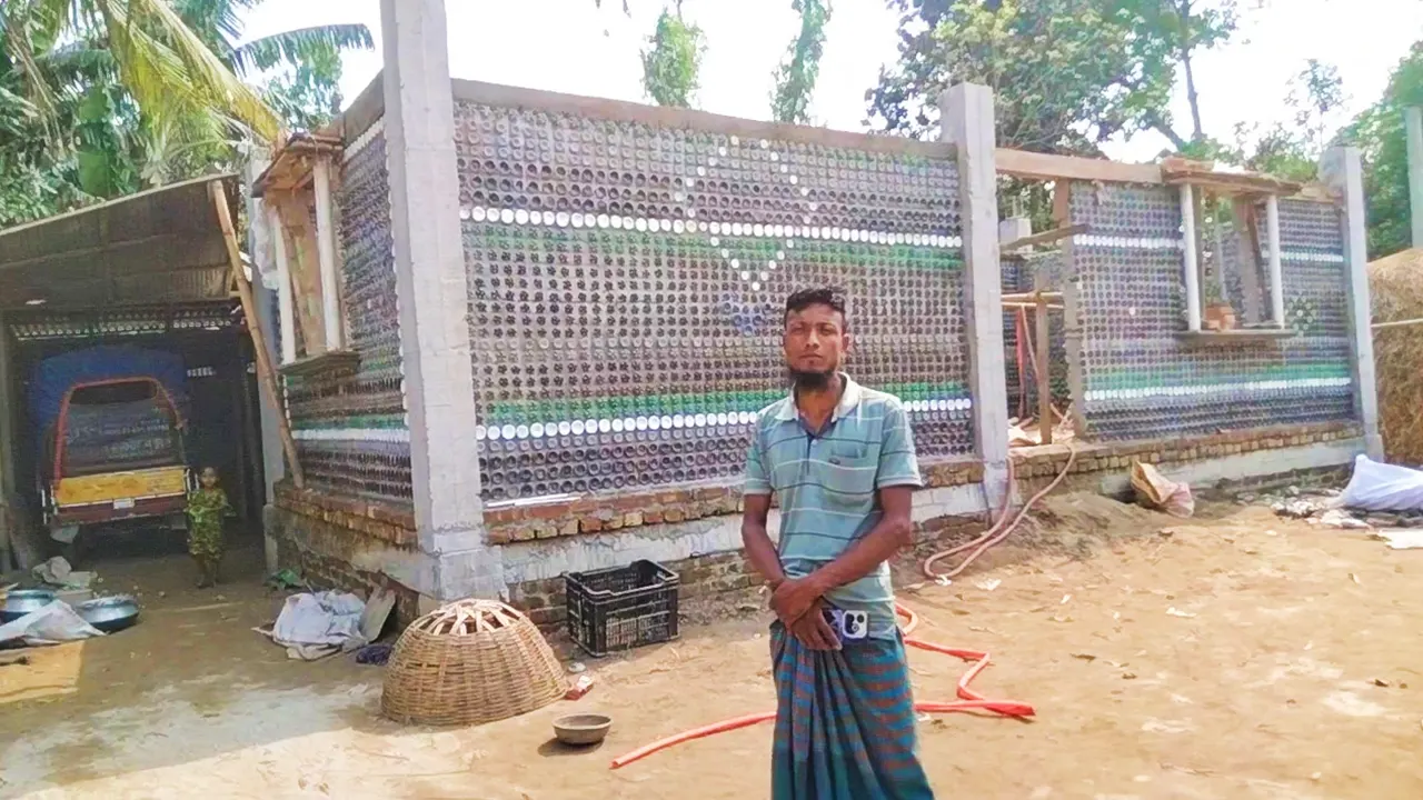 প্লাস্টিকের বোতল দিয়ে নির্মাণাধীন ‘বোতল বাড়ি’র সামনে মালিক আব্দুল হাকিম। ছবি : কালবেলা