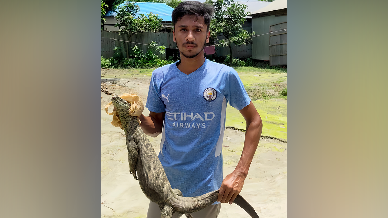 উদ্ধার গুইসাপসহ উদ্ধারকর্মী মাহামুদুল হাসান সোহেল। ছবি : কালবেলা