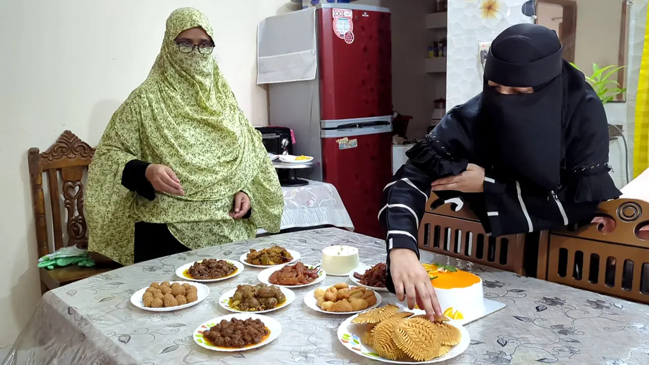 টেবিলে সাজানো কেক, পিঠা ও আচারসহ বউ-শাশুড়ি। ছবি : কালবেলা